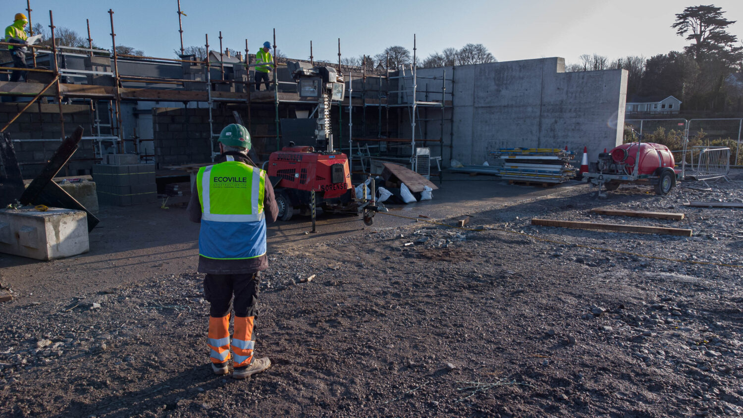 worker standing looking at men on scaffolding